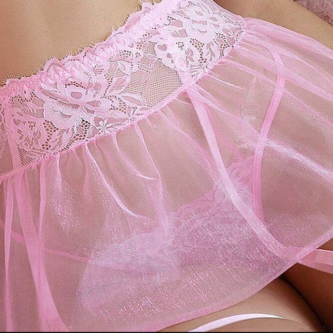 Person wearing a pink lace lingerie set on a soft, pastel-colored background